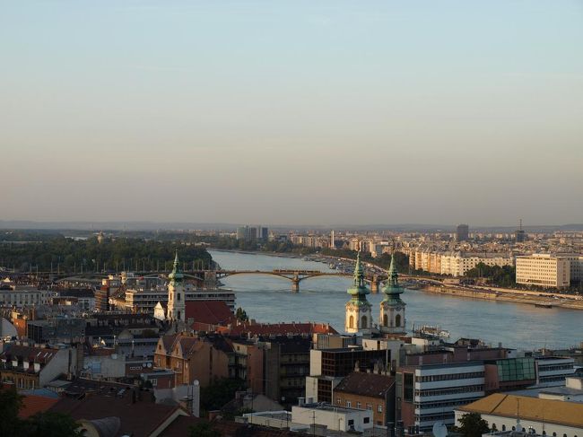 ドナウ川の上流方向を見ています。夕陽に染まる街並みが美しく、また遠くの山並みまで見渡せ、とても気持ち良い眺めです。<br />遠くの橋を路面電車が走っているのが見えました。
