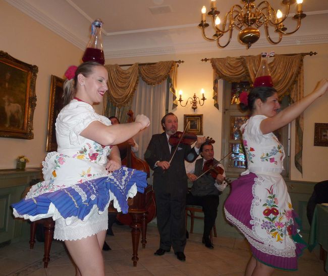 民族衣装で頭にワインを載せて踊る女性