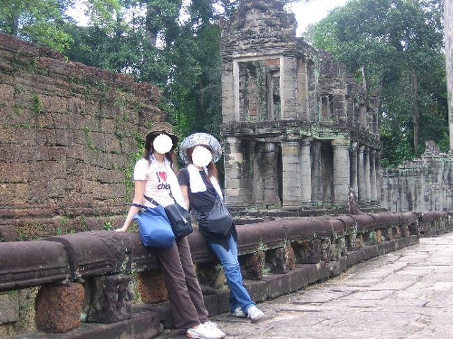 ナーガ像の一部。<br />奥に見えるのはアンコール遺跡の中でも珍しい二層構造と円柱状の柱を持つ建物。