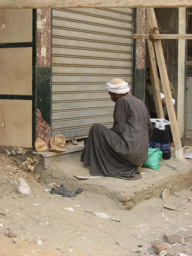 パンらしきものを売っているおじさん。<br />地べたに置いて売っています。