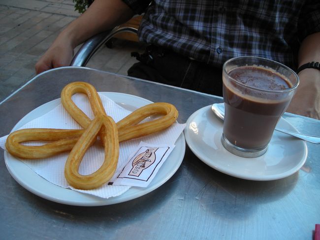 賑やかな広場にあるカフェでチョコラーテ・コン・チュロを食べる。<br />ディズニーランドのチュロスとは違うものなんですねー<br />甘くない、というか、塩味が効いている。<br />これをドロっとしたチョコレート(ココア？)につけて食べる。<br /><br />甘味と塩気の相乗効果でめちゃ旨！<br /><br />けど、おやつに１人分これだけは多すぎやしませんか？<br /><br />(チョコラーテ・コン・チュロ・３ユーロ、ペリエ・２ユーロ)<br />