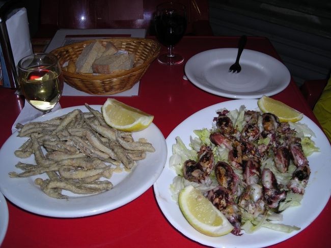 左はアンチョビのフリッター。<br /><br />おじさんは「アンチョビ」と言っていたけど、アンチョビってイワシ系だよね？けど、これは白身っぽい味。どちらかというとワカサギに近い味。<br /><br />サクサクに揚がっていて美味しいんだけど、こんなにたくさんはいらないよーーって量。<br /><br />右はかわいいイカちゃん。にんにくたっぷりで炒めてある。<br /><br />ここで出てきたパンは普通のパンとカリカリのラスクっぽいパン。柔らかいパンよりも乾いたカリカリパンの方がシーフードにはよく合いました。<br /><br />(＋ワイン２杯で２１ユーロ)<br /><br /><br />