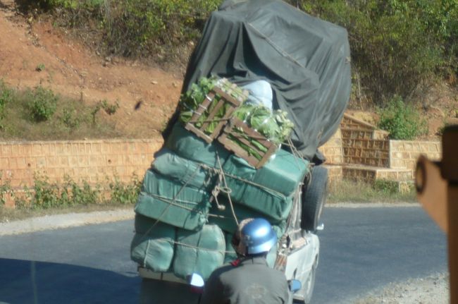 シャン高原をひた走り。　こんなに　大きな荷物を積み、　カーブにさしかかると、　大きく傾いていました。