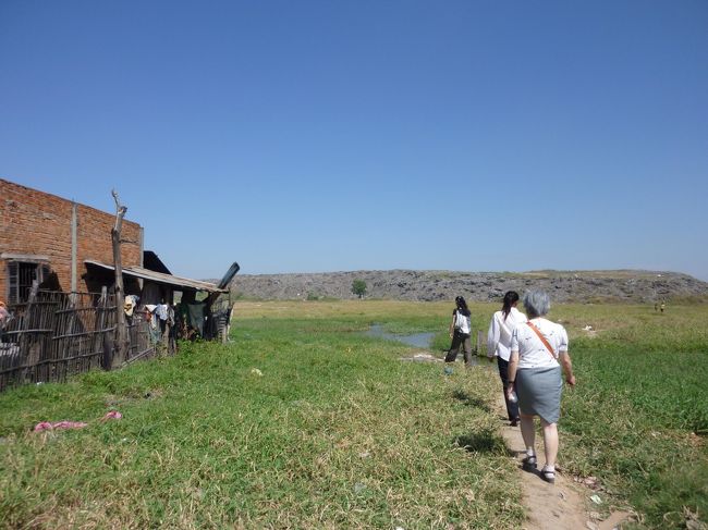 子供たちとつかの間の交流の後は　ここに着いたときから<br />きな臭い臭いと　悪い空気を運んできている　その発生源である　「ゴミ山」へ向かった。<br />むこうに山のように見えるのが　ゴミである。<br />長い間積み上げてきたので　遠目には土でできた山に見えるが　その実態はゴミ。<br />　