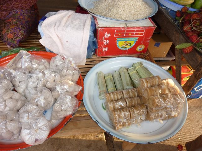 マイクロバスで今回の旅の目的地　プルサットへ移動の途中のトイレ休憩場所にて。<br />茶色で少し大きめのオセロの駒のようなものは　ヤシからとれたヤシ砂糖。<br />甘味はそれほど強くなくやさしい甘さ。<br />カンボジア常連さんお勧めのお砂糖なので　私も一袋買ってみる。<br />かじっておやつ代わりにもＯＫ。<br />たまにありさんも一緒に固まっているかも？<br />何でもありよ！<br />って、ダジャレかい？