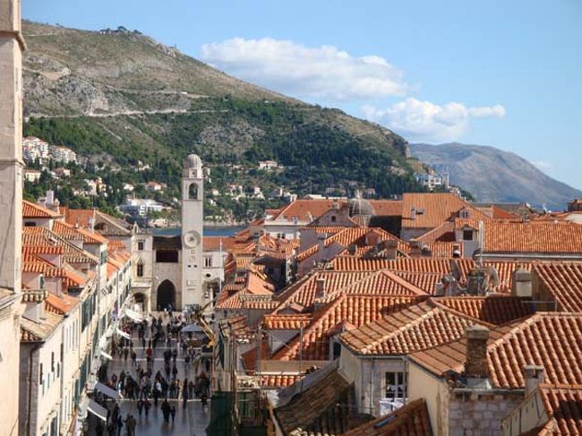 ←ドブロヴニクの城壁遊歩道からの眺め<br /><br />メインストリート、プラツァ通りから旧港の方角。<br />正面に見えるルジャ広場の鐘楼は毎時鐘が鳴ります。<br />