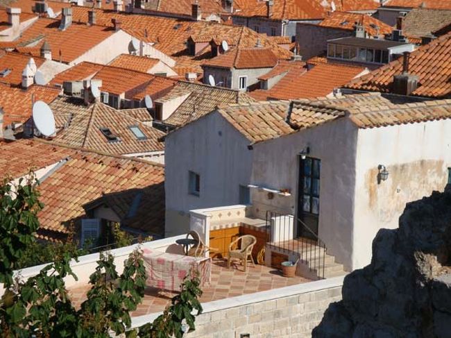 ←ドブロヴニクの城壁遊歩道からの眺め<br /><br />城壁に隣接する旧市街の住宅地。<br /><br />屋根の色が違うのは、爆撃で破壊されたものを修復した建物と古い建物が混在しているから。<br />色鮮やかな瓦は砲撃後に修復されたものです。