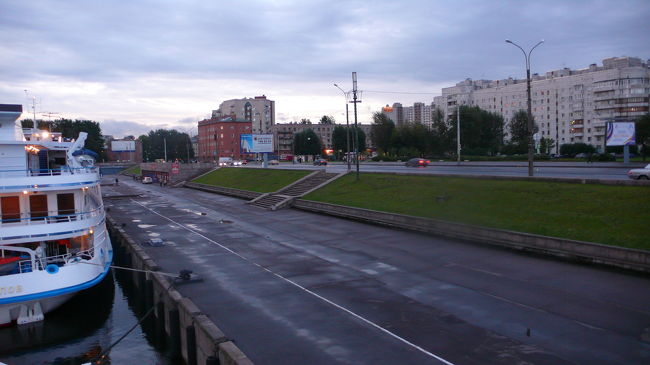 リトビノフ号から見た河港前の様子。<br />一般的なアパートが建ち並ぶ地域で、道路にはトロリーバスと電車が走っています。<br />左奥に見える赤い建物の左側には、スーパーマーケットがあり、食料品・家庭用品・酒・お土産品が比較的安く買い物が出来ます。<br />通貨は当然ルーブルのみの使用です。<br /><br />