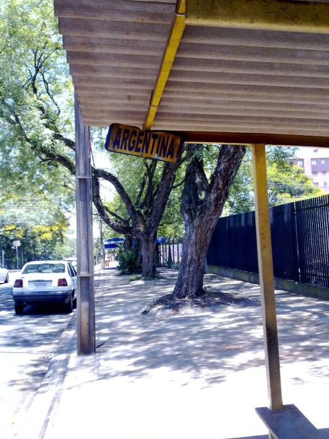 ブラジル側「フォス・ド・イグアス」から国境越えへ向かうバスを待つ。<br />「バス停」は、イグアスのターミナルの裏手にあって、こんなもんだ。「ARGENTINA」って・・・素っ気ない