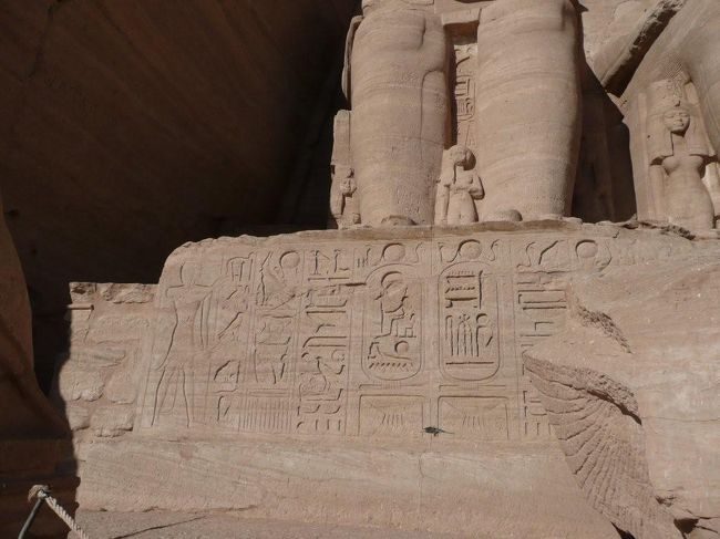 さらに足元の下にはヒエログリフの碑文が彫られている。もちろん読むこと出来ないので何て書いてあるかは全然わからない。<br /><br />そして足の右手に見える小さな銅像はこちらはラムセス2世最愛の妻と言われたネフェルタリの像。すごい髪型だな・・・。