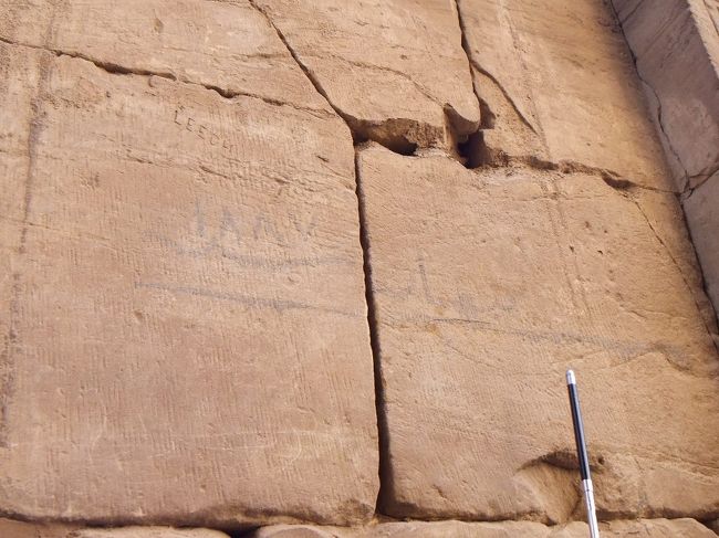 右側の第二塔門の側面あたりには、水平な線が引かれてその上にアラビア数字で「ＩΛΛＶ（１８８７）」と書かれています。これは、１８８７年のナイル川の水位です。右下に見えるのはガイドさんが説明のため振り上げた棒で、かなり高い位置にあります。