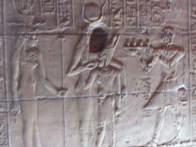 正面向かって右の壁の下側には、このようなレリーフがあります。中央のイシスが立ったまま、ホルスに乳をあげています。ホルスは普通ハゲワシの頭をしていますが、子供の時のレリーフなので子供の姿をしています。残念なことに、イシスの顔にぽっかり穴が開いています。コプト教徒（キリスト教徒の一種）の仕業らしいです。右側は多分、捧げ物をするファラオです。