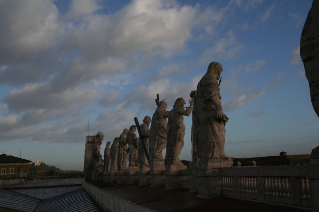 エレベータを降りたところまで下ってきました。<br />サンピエトロ広場を見下ろす彫像が並んでいます。<br />この屋上には、お土産屋さんもありました。<br />帰りはエレベータでなく、階段で下りました。かなりゆるい階段がずっと続いていて、下のほうには歴代法王名が書かれた大理石の板が埋め込まれていました。