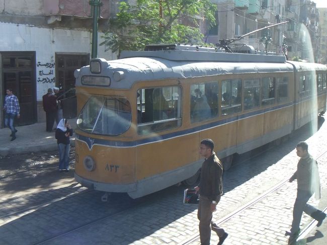 これはアレクサンドリアの路面電車です。狭い道を、路面電車もバスも人も通ります。９時５０分、カタコンベに到着です。一般の人の共同墓地だったところらしいです。写真撮影禁止なのでカメラはバスに置いて下さいと言われました。つまりません。ガイドさんの説明を聞きながら、中を見学しました。ガイドさんの説明は、昨日ホテルに行くバスの中で配られたイヤホンガイドで聞きますので、離れていてもよく聞こえます。ガイドさんは少しふくよかな方だったので、歩くのが大変らしく、ゼエゼエという声やゴホンゴホンという咳払いもよく聞こえました。荷物検査を受けます。エジプトの観光地には大抵、空港にあるのと同じようなＸ線装置と金属探知ゲートがあります。荷物はＸ線装置に通し、人は金属探知ゲートを通ります。そのままバッグを持って金属探知ゲートを通るところもあります。カタコンベはどちらだったか忘れましたが、いずれにせよ、ピーピー鳴っていようが、日本人ツアーの観光客はそのまま通過です。「入口にいるおじいさんにチケットを見せてあげてください」というガイドさんの表現、気に入りました。いくつか彫像が並んでいる中庭を進むと、井戸のような入口があります。井戸の回りの階段を降りていくと、色々なものがあります。一通り説明してもらいましたが、写真を撮らなかったので忘れてしまいました。靴箱を大きくしたような棚が並んでいました。骨壷を入れるところだったかと思います。骨が山積みになっている場所も記憶しています。これはカラカラ帝が大虐殺を行った時の人骨と伝えられましたが、調査によりレース用の馬の骨だということが分かったそうです。この骨のある所は滑りやすくなっています。注意が必要です。カタコンベは１４時まで見学。<br />