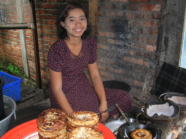 パンケーキのようなものを七輪で焼いて売ってた女の子。うっかり両替を忘れててミャンマーのお金を持っていなかったが、隣接した町だしタイのお金も流通してるだろうと思い、タイのお金を適当に出してみた。すると女の子は言葉が通じないので「ちょっと待って」というジェスチャーをしてどこかへ走り去って行った。<br />しばらくするともう一人女の子を連れてきた。パンケーキ屋の女の子はタイとミャンマーの通貨の交換比率を知らなかったのでお釣りをいくら返していいかわからず、知っている友達を呼びに行ってたのだった。 