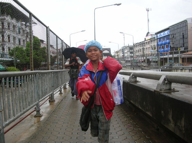 タイ側から戻ってくる人々。<br />シャワーキャップもアジアでは立派な雨具。 