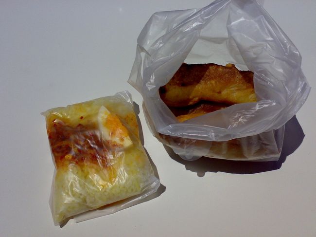 （右）バナナフライ RM1 (\25)<br />（左）ナシルマッ    RM1 (\25)… ココナッツミルクで炊いたご飯にスパイシーな小魚とナッツ、ゆで卵がのっている。<br /><br />袋の中で適当にまぜまぜして、隅っこに穴を開けて、そこから絞り出して食べる！