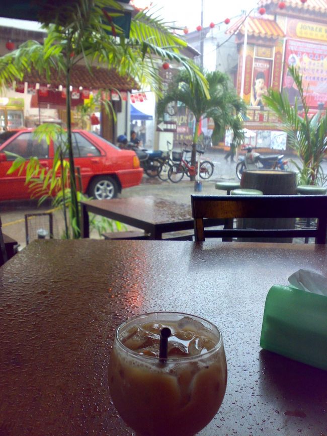 はい、やっぱり。<br /><br />自分の強運を信じて、チャイニーズレトロなカフェで雨宿り。<br /><br />テ O with ice RM2.7 (\67) … ミルクティー<br /><br />すぐやむと思ったのに、雷落ちまくりで激しくなる一方。<br /><br />クアラルンプール(KL)行きのバス発車30分前、マラッカ海峡からの夕日をあきらめる（泣）。<br /><br />傘なしでバス停まで歩いたら、まちがいなく風邪を引いて熱を出す。<br /><br />店員さんにタクシーを呼んでもらおうとしたら、そのうちの1人がバス停まで送ってくれることに。<br /><br />彼はミャンマーからの留学生21歳。<br /><br />心が洗われるくらいのイケメンだった。