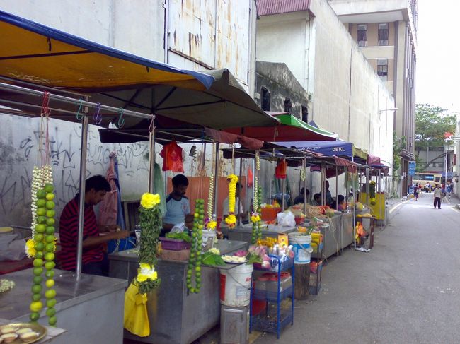 脇道には、お供え物を売る屋台が。<br /><br />手作業で繊細な生花や果物のリースを作っていた。