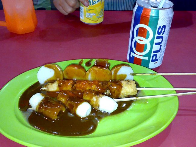 田楽的な甘辛のタレがかかってやってきた。<br /><br />あれはやっぱりただのちくわだったけど、練り物好きだからなんでもOK。<br /><br />後ろの100 PLUSも炭酸系スポーツ飲料だった。<br /><br />　おでん RM1×3 (\75)<br /><br />　ジュース RM1.8 (\45)