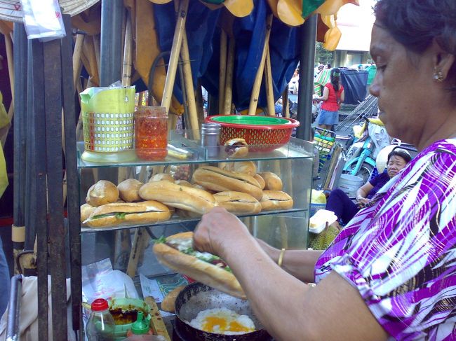 パンも食べなきゃ。<br /><br />　サンドウィッチ VND20,000 (\105)<br /><br />このちっちゃな屋台にコンロも付いていて、フライパンでふわっふわ卵を焼いてサラミなんかと一緒にはさんでくれる。