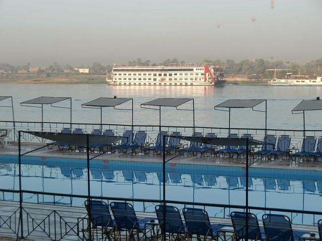 ガーデンプールとナイル川、ゆっくり就航するクルーズ船（写真）、そして、ルクソール西岸の上を気球が浮かぶ。