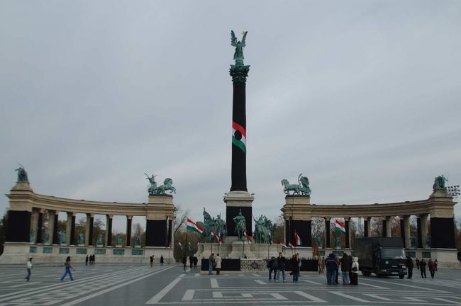 【英雄広場】<br />ハンガリー建国１０００年を記念して１８９６年に造られたブダペスト最大の広場。広場中央には大天使ガブリエルをいただく建国１０００年記念碑が立つ。<br /><br />ここでは何かの集会の準備をしており、記念碑に黒い布がかけられ、警備の警察官が配備されていた