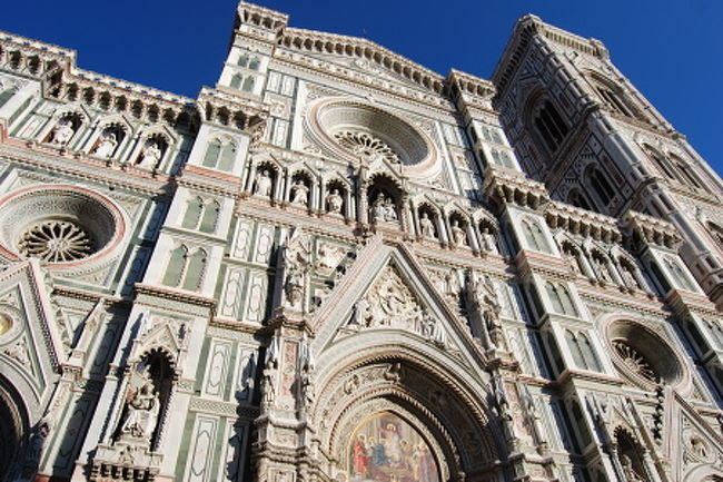 ドゥオーモの壁面は歴史家アウグスト・コンティが設計を担当したネオゴシック様式のファザード装飾が用いられています。<br />イタリア国旗の色である赤・白・緑の大理石で幾何学的な模様が造られています。<br />写真の中央上部に写っている円形の「バラの窓」の下に並んでいるのは聖母マリアと12人使徒の像。