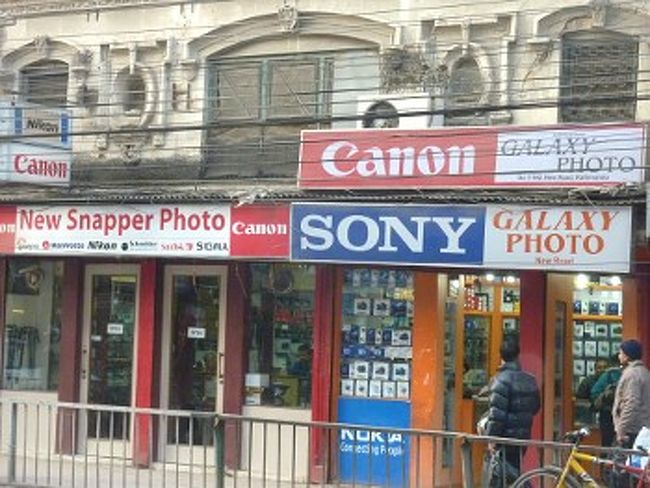 **この記事でいう「カメラ」とは、基本的に「デジカメ」を指します。<br /><br />[目次]<br /><br />　ネパールのカメラ屋　<br />　購入<br />　カメラ修理店<br />　修理の実際<br /><br /><br />[ネパールのカメラ屋]<br /><br />　ネパールでカメラ屋さんを探すのは至難の業です。カトマンズとポカラ以外では、現像ショップはあるかもしれませんが、販売店はまずありません。ポカラではレイクサイド、カトマンズではタメルに、それぞれ３，４店あります。以前はもっと少なかったので、ここ最近の動きです。ともに旅行者相手の商売のため、相場は高めです。ネパールでカメラといえば、やはりカトマンズのニューロード(写真)でしょうか。ここはローカル向けのお店が並ぶため、相場での購入が期待できます。残念ながらポカラには同様のカメラ街はありません。