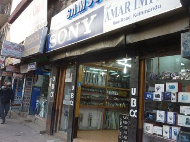 [購入]<br /><br />　ニューロードはダルバール広場のすぐそばにあります。この通りには、カメラ屋、コンピューター・ショップ、宝石店など、小金持ちのニーズに応えるお店が集まります。カメラは、中には割安な価格で売られているものもありますが、大半が「メーカー保証なし」の輸入品です。大手カメラメーカーは、ネパールに力を入れておらず、サービスセンターがないところが多いのです。商品はマレーシアなど他の国から持ち込またもので、保証がない以外は特に問題ありません。メーカーは、キャノン、ニコン、ソニーを中心に、オリンパス、パナソニック、サムスンと一通り揃っています。カシオ、リコーやサンヨーの製品は見たことがありません。<br />
