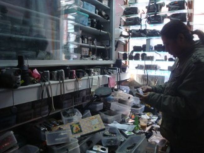 [修理の実際]<br /><br />　この手の店は、フィルムカメラ、デジカメ、一眼、ビデオカメラ、iPod、携帯などいろいろな製品の修理を行います。同ジャンルの製品は構造が似ているので、ネパールで流通していないモデルでも修理に応じます。<br /><br />　デジカメに話を限定すると、直せる故障と直せない故障の両方があります。キーパッドやズームの問題はたいてい修理可能ですし、部品交換も要りません。レンズ内部やCCDの汚れもクリーニング可能です。ただ、CCDに傷がある場合は、CCDを交換するしかありません。推測ですが、水没などで基盤や液晶が壊れた場合は、交換部品がある場合を除き修理できないと思われます。<br />