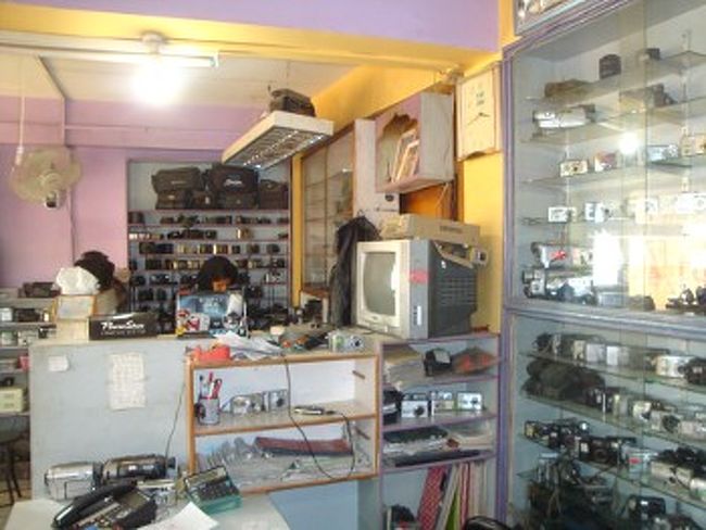 　店の中に入ると、小奇麗なオフィス(写真)と作業スペースがあり、意外と洗練されています。手順としては、受付で故障箇所を説明し、見積もりもらいます。料金に問題なければメモリーカードを抜いて修理に出します。修理料金は、私の感覚では、「めちゃくちゃ安いわけではないが、かなり安い」というのが感想です。ズームレンズの分解が必要な複雑な作業で1500ルピー(1800円)くらい。単純な修理だと、当然もっと安くなります。