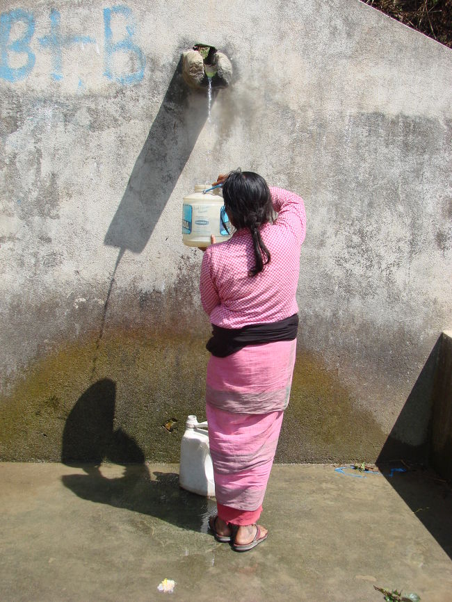 ちょろちょろと流れ出る水を気長に汲み取る小母さん。