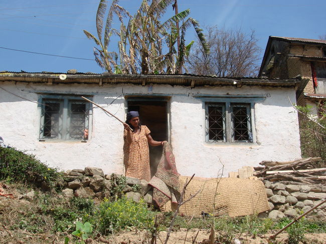 カーペットを叩いて埃をとっている小母さん。