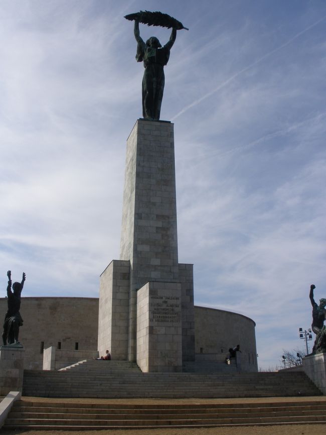 ゲッレールトの丘の棕櫚の葉を高く掲げる女性像のもとで<br /><br />心臓だけはまだはドキドキ状態だけど、<br />まるで何事もなかったかのような風景に<br />だんだん頭の中がはっきりしてくる・・・<br /><br />え〜〜〜？？？<br />私、ここに居るよね？<br />さっき出会った人ってナンだったの？<br /><br />一瞬の事だったようで、すごく長かったようで<br /><br />しばらくここで、あの男が居ないかどうか<br />恐る恐る辺りを眺め回し、<br />居ないことがはっきりし、しかも、<br />アイツは下のほうへ下って行ったし<br />他にも観光客が何人かいるのを見て一安心