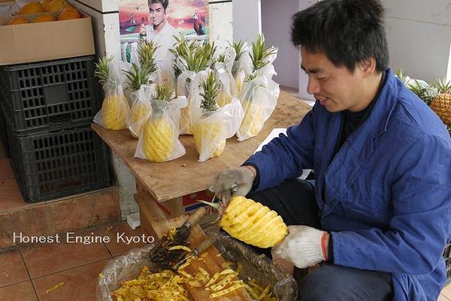 市場の外周の果物屋では、パイナップルを上手にカットする人がいました。