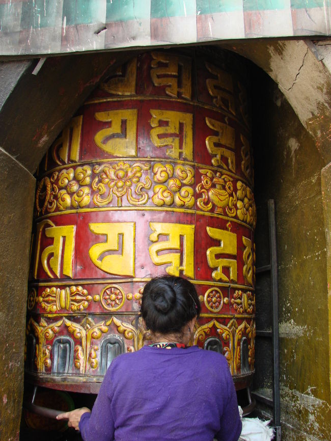小母さんが大きなマニ車の拭き掃除をしている。