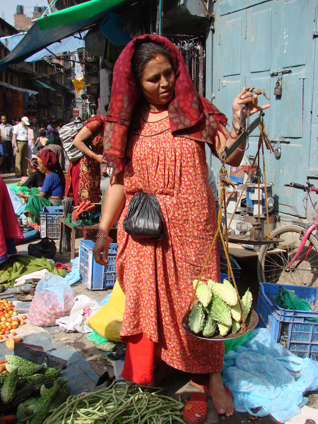 小さな市のある通り、ゴーヤ（苦瓜）の重さを量っている小母さん。