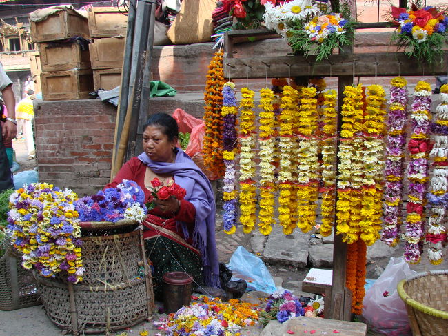 数珠繋ぎにした献花を売る小母さん。