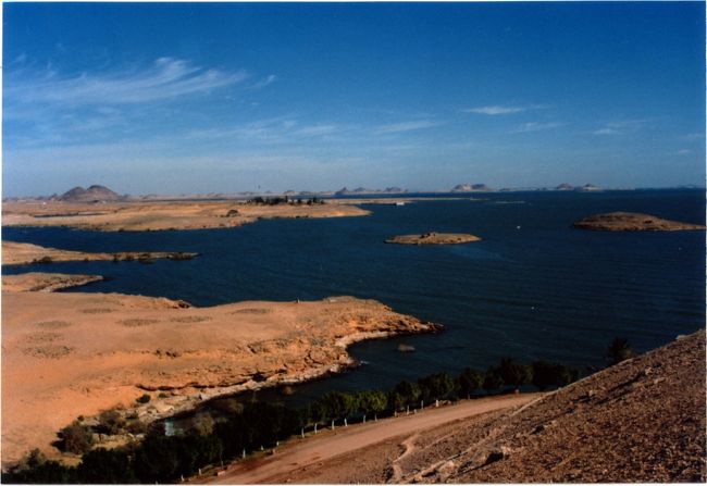 旅日記<br />『アスワン・ハイ・ダム』<br /><br />アスワンの街からバスで３時間、砂色の景色に鮮やかな青が加わる。<br />「アワンハイダムに着きました」と、ガイド。<br />「ここが？」と、乗客。<br /><br />ダムというからには見上げるようなコンクリートの堤防を思い浮かべていたのだが、足元に広がるダムは「琵琶湖に着きましたよ」と言われても信じてしまうぐらい人工的な建造物がない！<br />見上げるような堤防も無く、足元に広がるのは、ただの砂利でできた土手だ。<br />唯一異なる光景は、辺り一面、銃を携帯したエジプト軍がうろついている事だけだろうか？<br /><br />さすが、「エジプトの生命線」と言う所か。