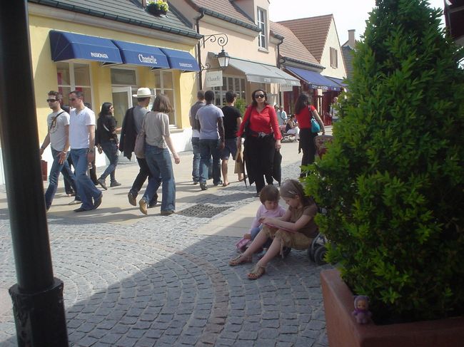 アウトレットはたくさんの人でにぎわっています。<br />お買いものに飽きた子供たちはママを外で待っています。