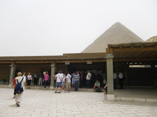 ピラミッドへ向かう途中、ちょうどピラミッドが見えてきて、ヒーマさんが「ピラミッドが見えてきたよ〜！」って言ったのですが、あたし達は「ぉ〜」くらいにしか反応せず（何しろ、午前中ず〜っと部屋から眺めていたので・笑）、「ピラミッドが見えてきて、こんなに反応が薄いお客さん初めてだよ〜。僕のためにもう一度喜んで！」って言われ(笑)、「きゃ〜♪ピラミッド〜!!!!」って喜んでみました（＾＾；<br />いや、心の中ではドキドキしていたんですよ、もちろんアノ有名なギザの3大ピラミッドへ行けるわけですから♪♪<br /><br />あたし達は、クフ王のピラミッド横からピラミッドエリアに入場しました。こちらが入り口。<br />ちゃんとセキュリティチェックを受けます。