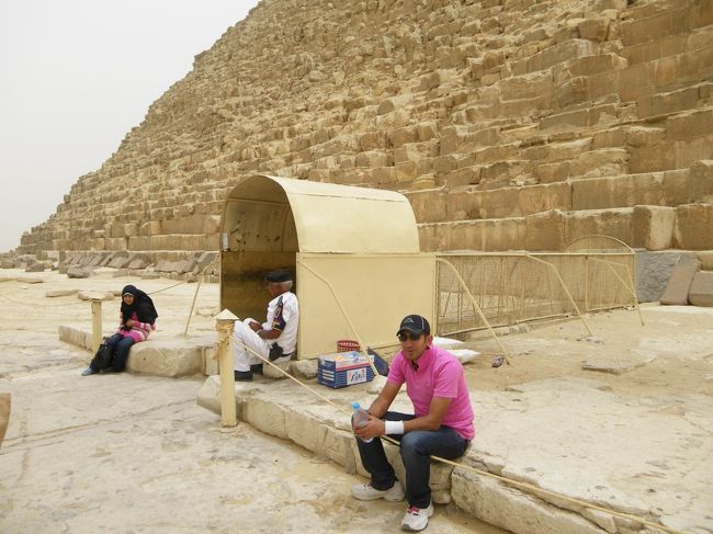 【カフラー王のピラミッド】☆<br /><br />あたし達は、第2ピラミッドのカフラー王のピラミッド内に入場しました！<br />ピラミッド同士はけっこう離れているので、全部車で移動します。<br />ここが、カフラー王のピラミッド入り口。<br />（ちなみに、ピンクのシャツがヒーマさんです♪）<br /><br />内部は撮影禁止なので、ヒーマさんにカメラを預けていざ入場!!!<br />最初の方はそうでもありませんでしたが、だんだん狭くなってきて、階段を中腰、そして座って下りていくような形になって足がぷるぷるしました(笑)<br />あっちゃんは、これのせいで翌日筋肉痛で階段が下りれないって何度も言ってたほど(笑)<br />そして、暑さも臭いも最初はそうでもなかったけど、奥に入ったらサウナ状態＆なんとも言えないこもった臭いで、汗だくになりました。<br />中は何もなくてからっぽだけど、ピラミッドの中に入ったっていう事実だけで、あたしは十分♪♪<br /><br />この日は、砂嵐で曇っていたせいか、エジプトといえどもあまり暑くなかったです（でも、日本の夏で曇りの日くらいですが）。<br />なので、ピラミッドから出た瞬間は、一瞬涼しく感じました（＾ー＾）