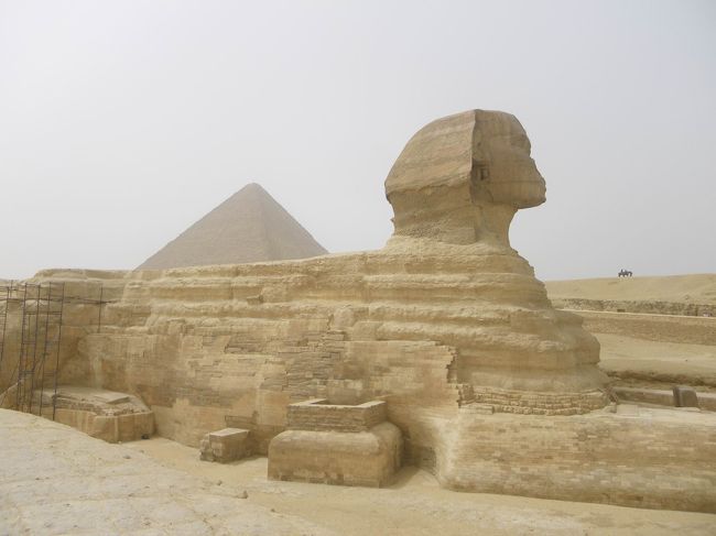 スフィンクスが姿を現しました〜!!!!!<br />顔は人間、体はライオン。大きな一つの岩を削って造られた、世界で一番大きなスフィンクスです♪<br />エジプトに行ってみたいと思いながらも、つい最近までスフィンクスはたくさんいるって知らなかったあたし…（＾＾；<br />色んな所に、小さなスフィンクスはいたんですね。<br /><br />ここでもおもしろい写真が色々撮れるよ！ってヒーマさんが教えてくれました。<br />例えばこれは、一見普通ですが(笑)背中にピラミッドを乗せたスフィンクス。<br />あとは、お決まりのスフィンクスとのキス写真なんかも。<br />ここには小さな子供達がたくさんいて、パピルスや香水瓶を1ドル1ドル〜ってそれはそれはしつこいくらいに言ってきました。<br />カメラを奪われ写真を撮られようものなら、また1枚1ドル〜って…あっちゃんはとてもテンションが下がっていました。