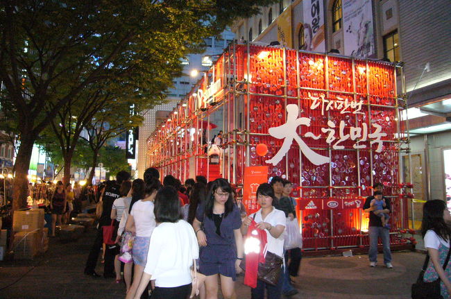 夜の明洞。もう、ほんとにどこもこんな感じです。<br />もちろん６月１２日（土）は大雨の中、私たちも赤いＴシャツを買って着替えて、市庁広場のパブリックビューイングへ行きました。今回の旅にそもそもパブリックビューイングへ出向く、なんて予定にはなかったのですが、もう金曜日あたりから街を歩く人の赤Ｔシャツ率がどんどん上がってくる。これはもう行くしかない！と。<br />残念ながらそのときの写真はありません。人もいっぱい、大雨で写真取れる状態ではなかったのです。<br />この日ギリシャに勝った韓国。夜中まで「大〜韓民国」コールが町中のあちこちで聞こえていました。<br />サッカー、ここまで熱いとは！