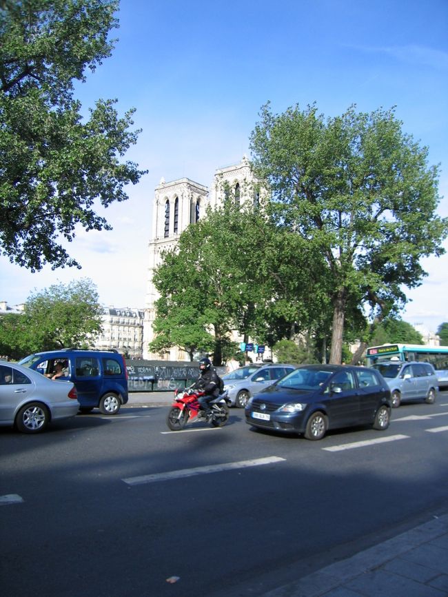 空港を出て、郊外を走る。<br />暑い。<br />運転手さんも窓を開け放して走る。<br />パリってこんな暑いのか・・・。<br /><br />メーターがちゃんと動いているかさりげなく確認・・・大丈夫そうだ。<br /><br />郊外の雰囲気は、だいたいどこの国も似たような感じなんだなあ、と思う。<br />マンションぽいものや、郊外型ショッピングセンターみたいなものを通り過ぎていく。<br /><br />途中、日本でたまに行く北欧の家具店「ＩＫＥＡ」があって、おおと思う。<br />ＩＫＥＡって、フランスにも進出してるのか。<br /><br />３、４０分走ったろうか、運転手さんが指さす。<br />「ここからパリの中心部だよ。」（たぶんそんな感じのことだと思う(笑)）<br /><br />そう言えば、街並みがパリっぽくなってきた。<br />その変化は割と唐突だ。<br />カフェが見える。<br />おお〜パリだあ！<br /><br />そして気がつくと右手にセーヌ河が。<br />そうか、ここは左岸だ。<br />なんとなく右岸のオペラのあたりからパリに入るのかと思っていたのだけど・・・。<br /><br />たくさんの車。<br />熱気。　歩道にはたくさんの人々が行きかってる。<br /><br />やがて右手にノートルダム寺院らしきものが！<br />それに河岸には古本の露店のようなもの・・・ブキニストだあ！<br /><br />本で見たそのままの風景が目の前に。<br />ついにパリにやってきたんだ。<br />でも、実感がわかない。<br />どちらかというと、予想外の熱気と周りの光景に圧倒されてしまった。<br /><br />車はのろのろと進み、いよいよ人が多くなってくる。<br />パリってこんなににぎやかなんだ・・・。<br /><br /><br /><br /><br />