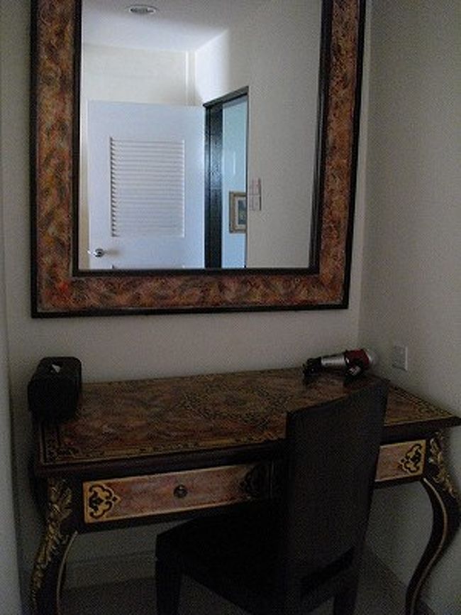 そのドレッシングデスク。<br />でっかい鏡にドライヤー、ティッシュが備え付けられている。<br />確かに私もここに化粧品その他を置いて、スキンケア＆メイクをする場所として使用。<br />しかーし！　鏡の位置が高すぎて、椅子に座るとおでこから上しか見えない！！<br />なのにムダにでかい鏡。