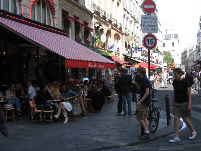 通りの角のカフェのテラスでくつろぐ人々。<br />ああ、まさにまさにパリの光景ではないか。<br />今さらだけど、本当にパリってこうなんだ。<br /><br />ビッシュ通り〜サン・ミッシェル広場までの通りは歩行者天国のようになっていて、カフェのテラス席がずうっと続いている。<br />すぐそばを人が通りすぎてもみんな気にもとめないように、会話に興じている。<br />その様子がすごく自然で、当り前だけどすごくなじんでいて・・・<br />そんな人々の間をぬうようにして進んでいると、なんとなく自分が場違いのようなちょっと寂しい感覚になってしまう。<br />やっぱり自分はこの地ではよそ者なんだなあ、というような・・・。<br /><br />滞在中、パリは何度か私をそういう心地にさせた。<br />それは、パリの人々がいかにも「楽しんでいる」気配を見せていたからだと思う。<br />平日の夜であっても、カフェのテラスで仲間と食事と会話を共にしている。<br />なんというか、その会話の濃度が日本で見る人々のそれとは違うように見えたのだ。<br />それは、フランス語と日本語という言語の持つ特徴の違い、それを発する時のリズムや身振りの違い、のようなものからもきているのかもしれない。<br />でもそれ以上に、カフェのテラスで見たパリの人々には、「その時間を生きている」オーラがあった。<br />あの雰囲気は、日本ではちょっとお目にかかれない。<br /><br /><br /><br />