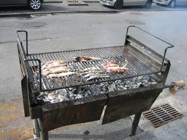 ポルトガルに来る前に、あちこち探した個人のホームページで、マトジーニョスという地下鉄の終点にある港町で、道沿いにおじさんがドラム缶を半分に割ったようなコンロで魚を焼いて食べさせてくれるお店があるという情報がありました。<br />地下鉄の路線図を見てみると、確かにそういう名前の町があるようなので、とりあえず終点まで地下鉄で行ってみることに。<br />駅の周りはどう見てもコンテナが山積みの商業用の港で漁港の雰囲気はかけらも無い。線路に沿って歩いて2駅ほど戻りながらぶらぶらするうちに漁港らしい雰囲気になってきて、とうとう目指すマトジーニョスの街に到着。<br />海沿いの道にドラム缶のコンロを並べているお店が何軒もありました。