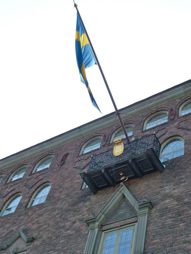 　真っ先にやってきましたのは、あの益川先生も来られた、ストックホルムの市庁舎でございます。<br /><br />　ご同行の方で益川先生と高校で同期生だったという方がおられて、びっくりです。やはりチョコレートをお買いになったのでしょうか。<br /><br />　やっぱり多くの観光客が殺到するポイントであるらしくて、とてもシステマティックな見物管理がされているようです。<br /><br />　ガイドの方がご説明下さっているところで、ちょっと離れて写真を撮ろうとしていたら、赤いポロシャツを着た係員の女性が寄ってきて「グループから離れるな」といいます。<br /><br />　どんどん平気で奥まで入ることのできてしまうコペンハーゲンの市庁舎と較べたら大違いです。